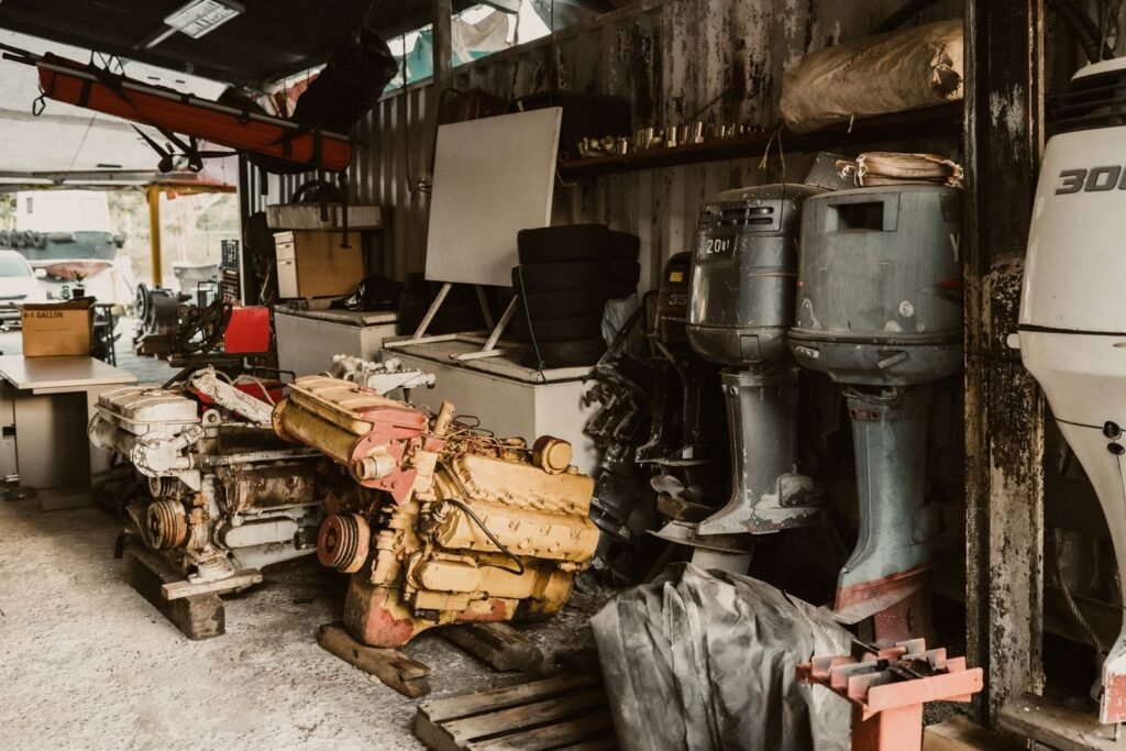 Workshop interior with car engines on pallets and outboard motors on a rack